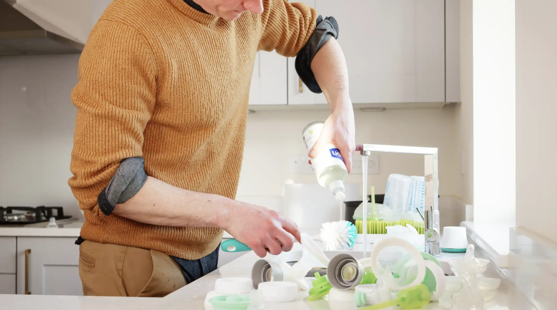 A friendly support worker helps with washing dishes in a clean kitchen.